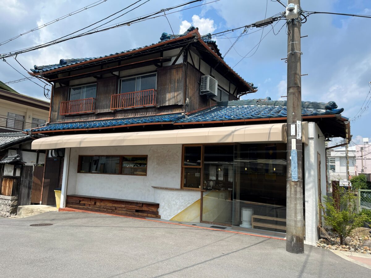 青い瓦屋根と白壁のcurationの外観