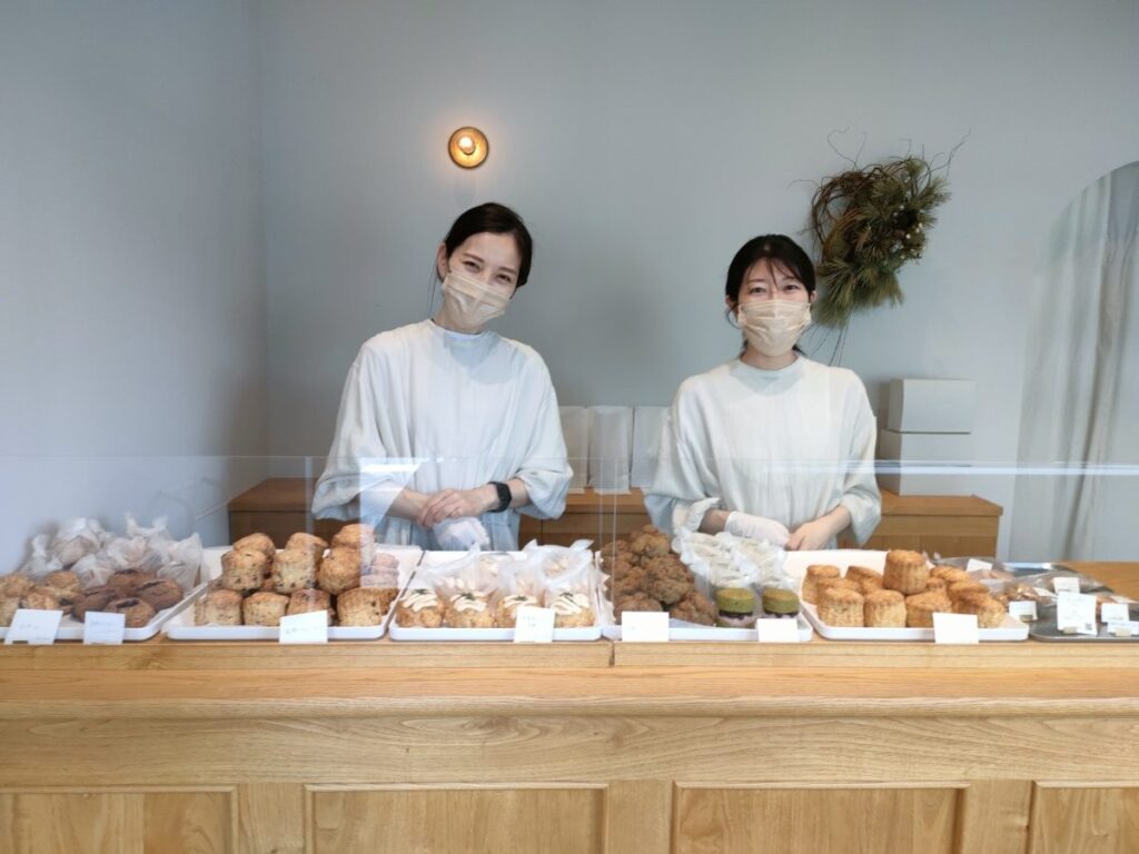 白いカウンターに並ぶスコーンとお店の方｜スコーン屋つむぎ